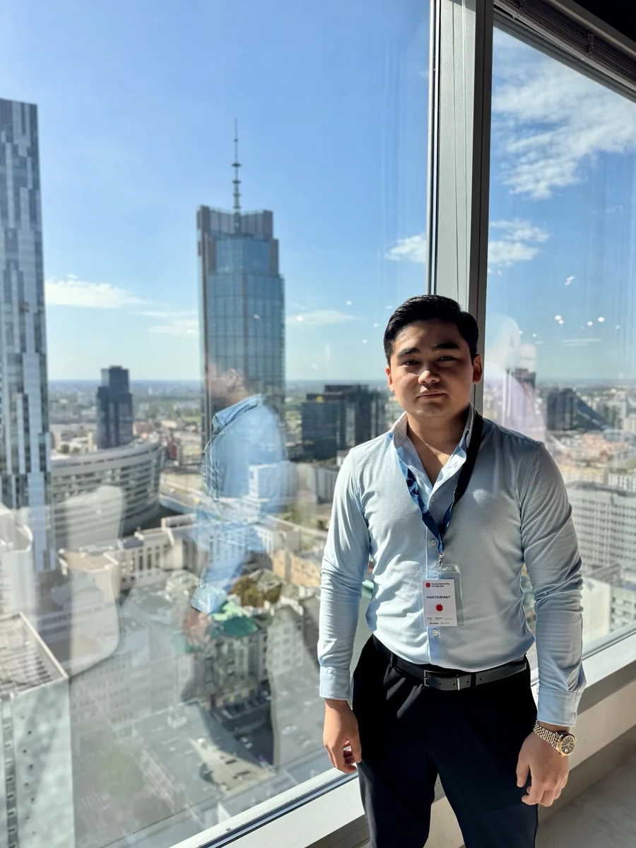 Sodik Tursunboev at a cybersecurity congress, with the Warsaw skyline behind him